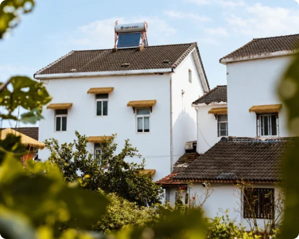 Residential-style guesthouse property with an integrated roof-mounted solar water heating unit featuring a solar thermal collector and horizontal storage tank.