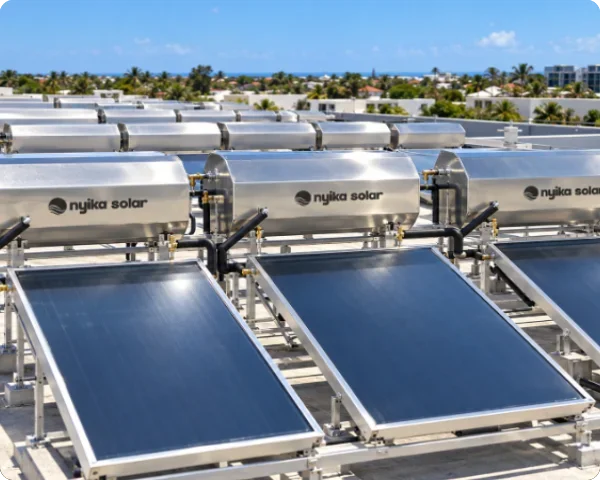 Multiple Nyika Solar integrated solar water heating units arranged in rows, featuring flat-plate thermal collectors and horizontal stainless steel storage tanks.