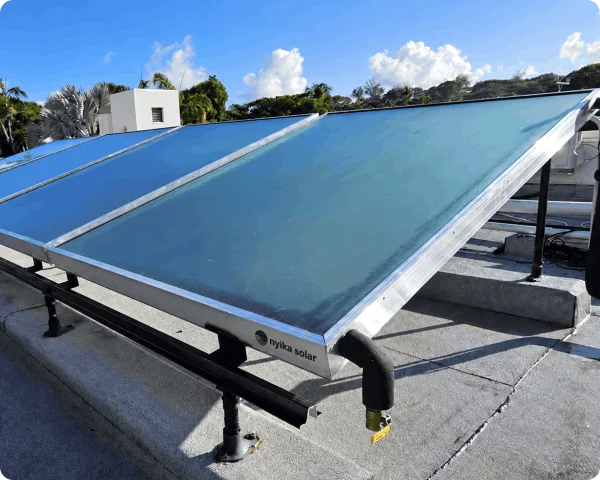 Close-up of large inclined flat-plate solar thermal collectors with metal mounting supports and connected circulation pipework.